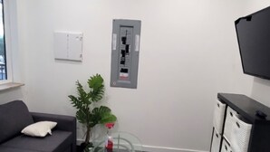 Ett modernt rum med en grå soffa, ett glasbord med en växt, ett svart skåp och en väggmonterad TV.