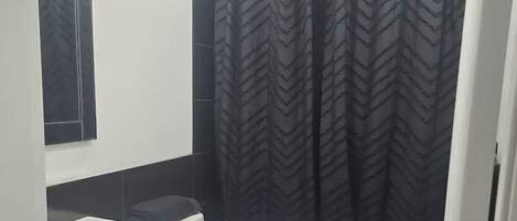 A modern bathroom with a white toilet, a black sink, and a shower curtain with a chevron pattern.