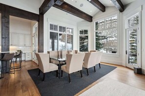 Un espace repas moderne avec une table en verre, des chaises de couleur beige et un tapis noir.