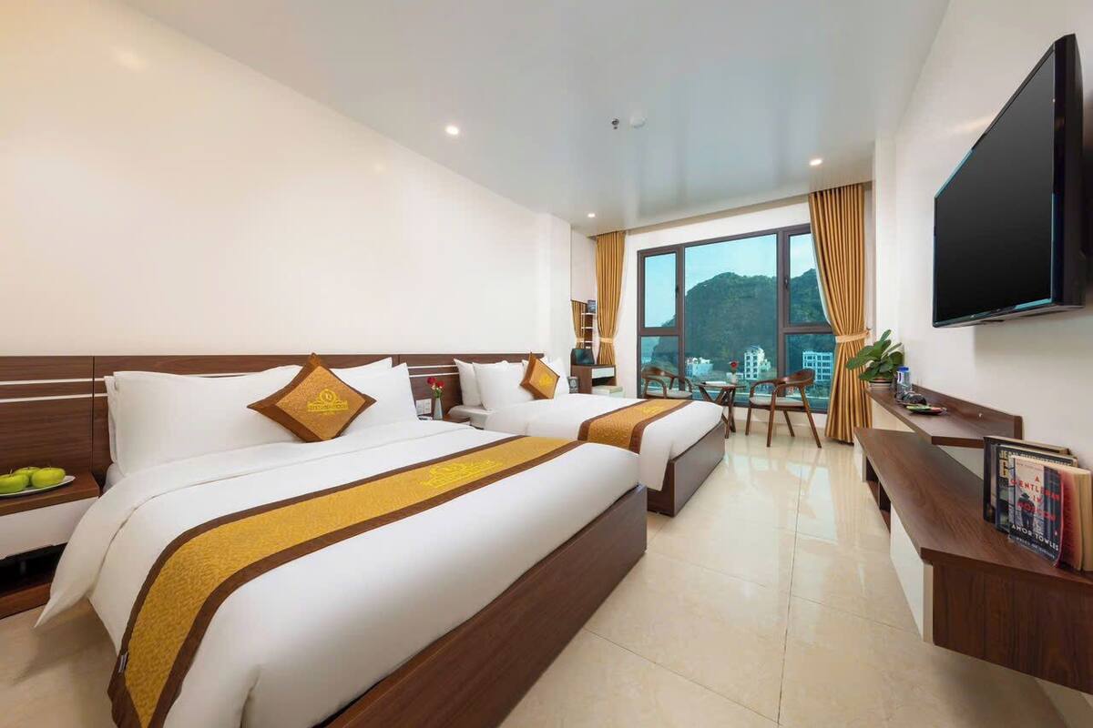Habitación de hotel con dos camas, un escritorio, un televisor y vistas a la montaña.