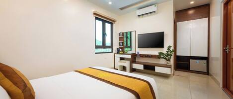A modern hotel room with a large bed, a TV, a desk, and a wardrobe.