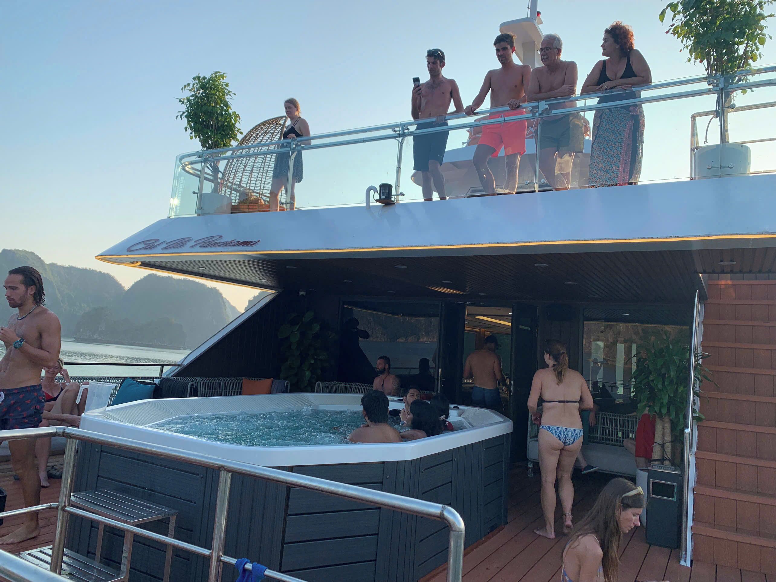 A yacht with a hot tub, outdoor seating, and a deck area with people.