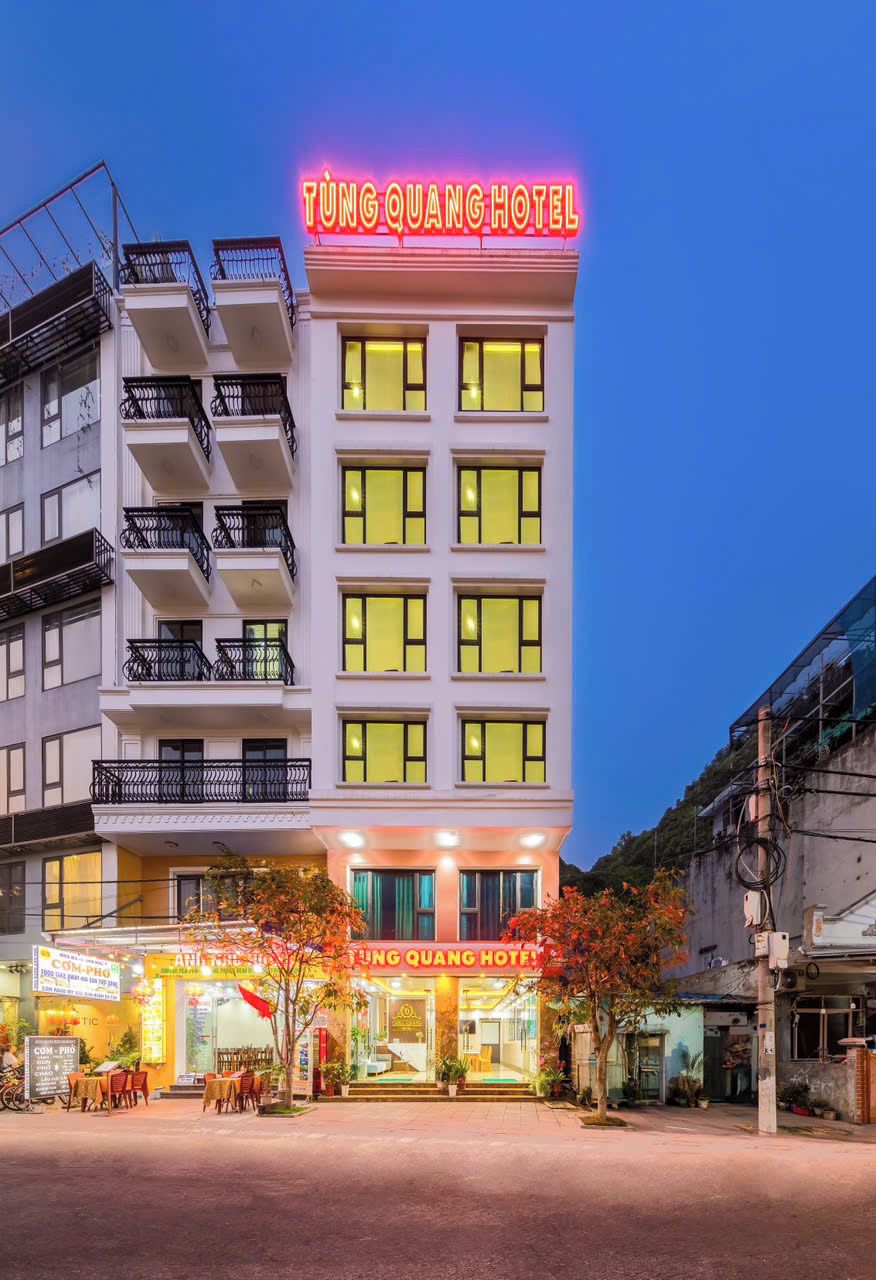 Ein Hotel mit einer Neonreklame, mehreren Balkonen und einem gut beleuchteten Eingang.