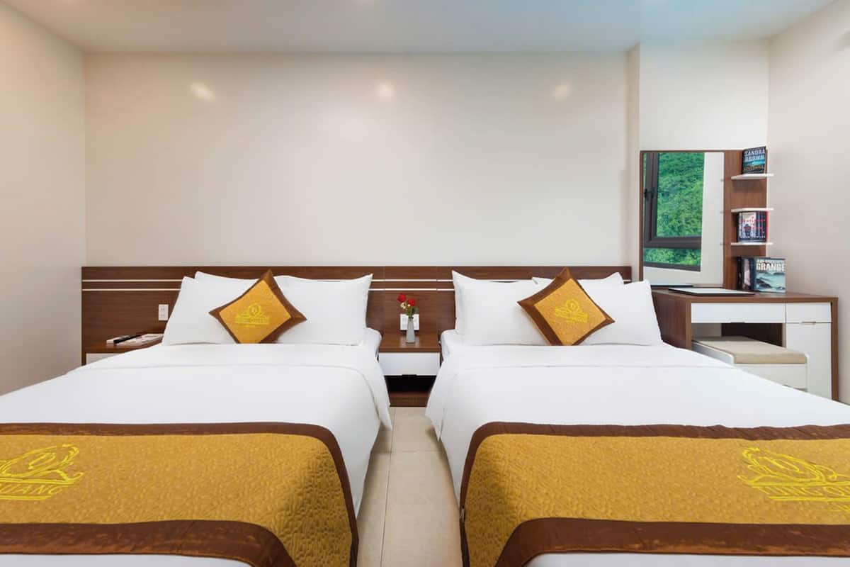 Una habitación de hotel con dos camas, un escritorio pequeño y una estantería.