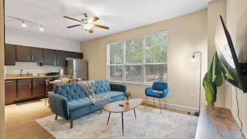 A modern living room with a blue sofa, a coffee table, and a TV mounted on the wall.