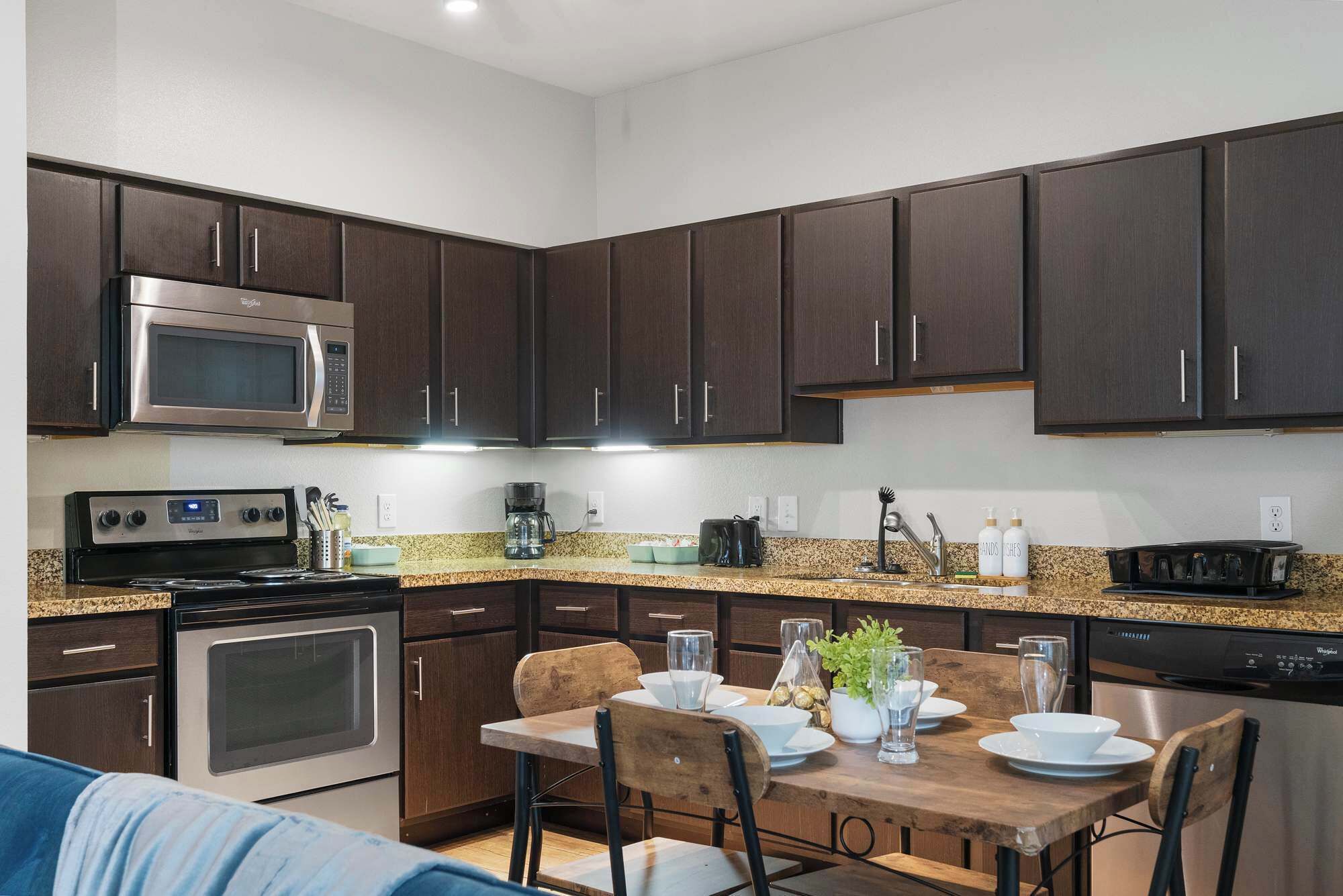 A modern kitchen with dark wood cabinets, stainless steel appliances, and a granite countertop.