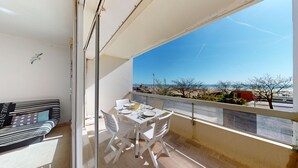 Ein Balkon mit Tisch für zwei Personen, mit Blick auf einen Strand.