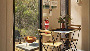 A modern room with large windows, a fire pit, and a view of trees. - Eucalypt Escape by Tiny Away (Coimadai)