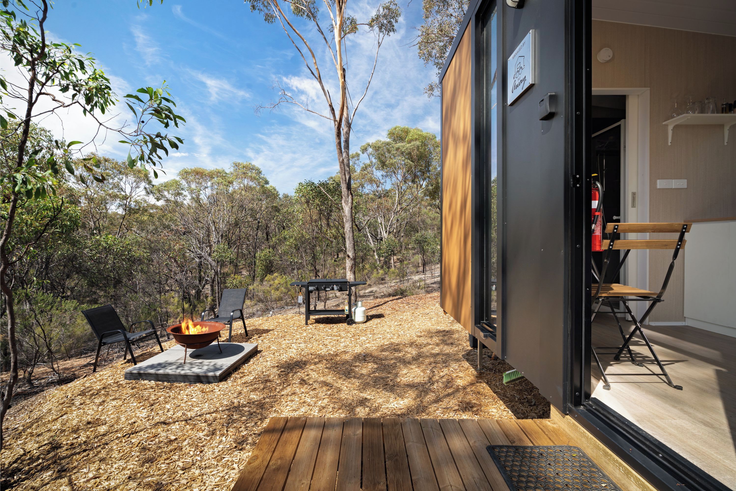 An outdoor patio with a fire pit, seating, and a view of the forest.