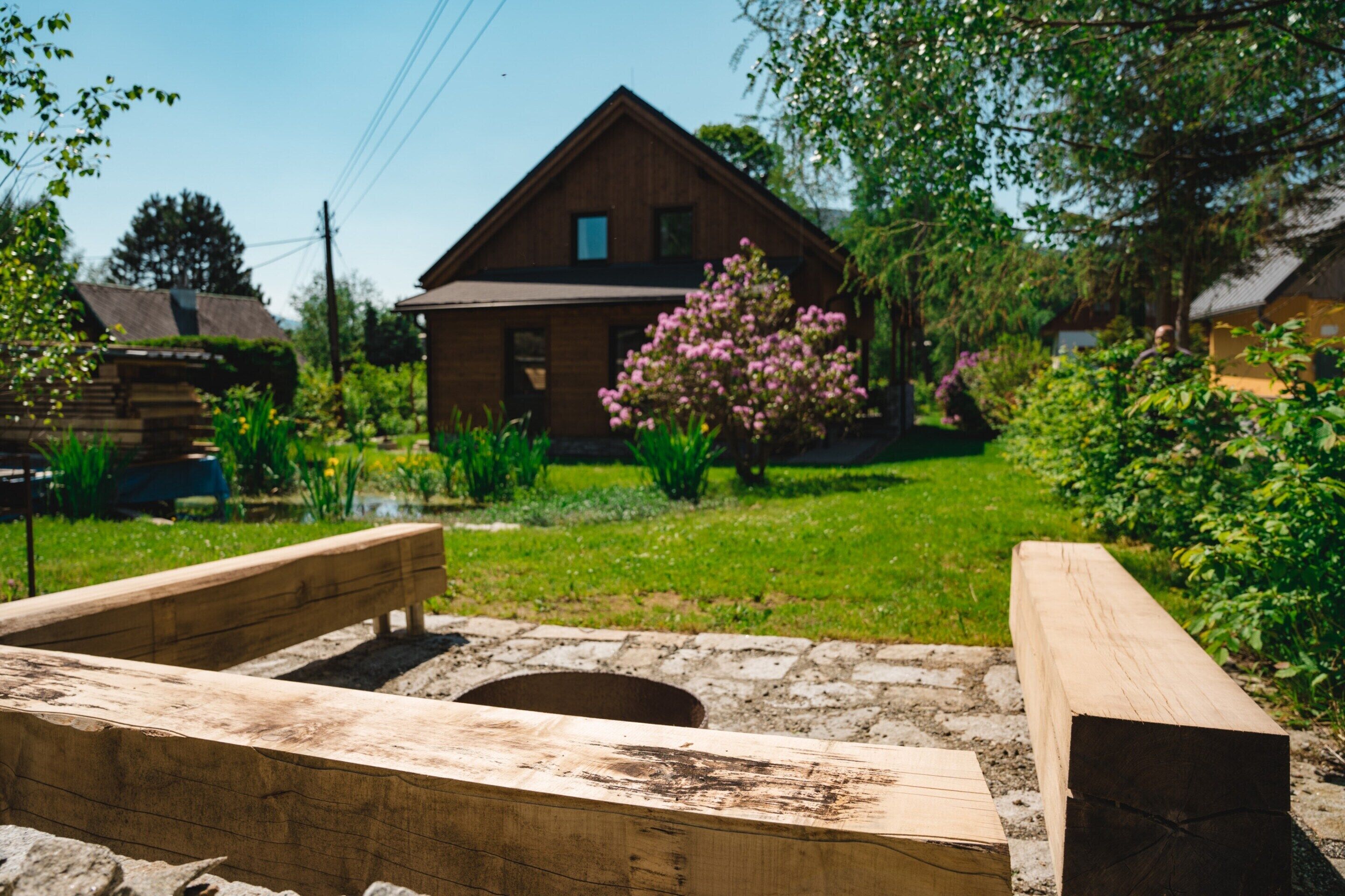 A wooden bench in a garden with a house in the background.