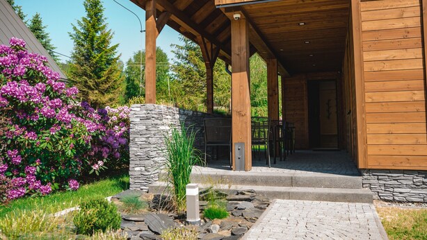 A wooden cabin with a stone exterior wall, a covered porch, and a stone pathway leading to the entrance. - Villa in Jeseniky With Sauna & Mountain Views (Bela pod Pradedem)