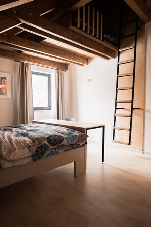 A bedroom with a bed, a window with curtains, a desk, and a wooden ladder. - Villa in Jeseniky With Sauna & Mountain Views (Bela pod Pradedem)