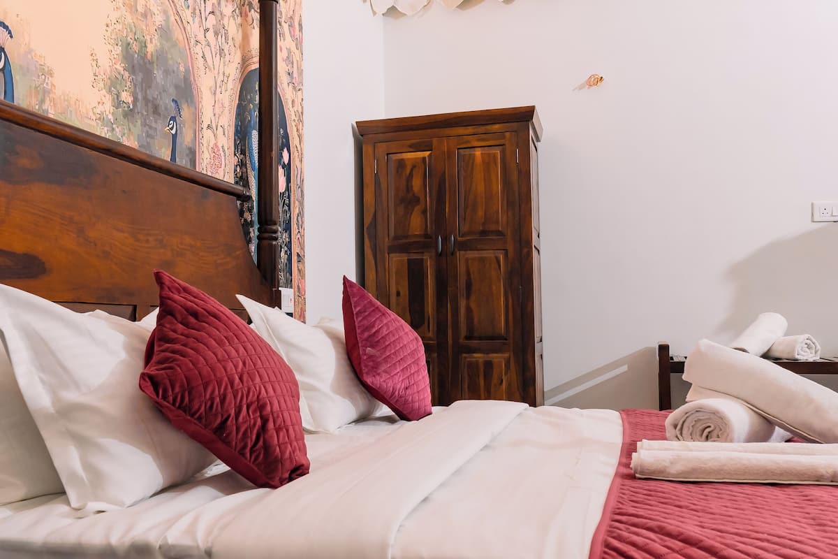 Una cama bien hecha con almohadas blancas y rojas, un cabecero de madera y una colcha roja.