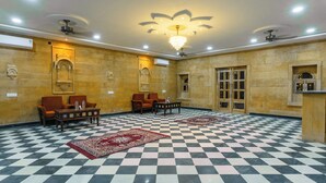 Un hall con piso a cuadros, dos sofás, una mesa de centro y una araña.
