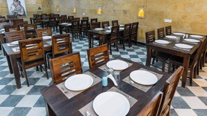 Un restaurante con varias mesas y sillas, dispuesto sobre un suelo de patrón escocés.
