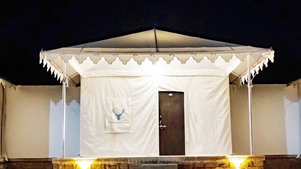 Una carpa con un logo, una puerta y unos escalones que conducen a ella.