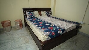 A bedroom with a bed, two wall sockets, and a marble floor. - Om Trance Homestay (Jaipur)