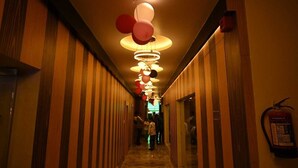 A hotel hallway with striped walls, a fire extinguisher, and a ceiling with hanging spherical lights. - HOTEL MANNAT INTERNATIONAL (Kanthi)