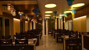 A restaurant with multiple tables and chairs, warm lighting, and hanging spherical decorations. - HOTEL MANNAT INTERNATIONAL (Kanthi)