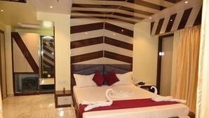 A hotel room with a modern design, featuring a large bed with a red and white striped headboard, a marble floor, and a unique ceiling pattern. - HOTEL MANNAT INTERNATIONAL (Kanthi)