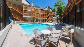 A poolside area with a clear blue pool, wicker chairs, and a staircase leading to a building with balconies. - NEW Central Buckhead Apt Atlanta Gem (Atlanta)