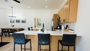 Una cocina moderna con una isla central, armarios de madera y taburetes altos negros.