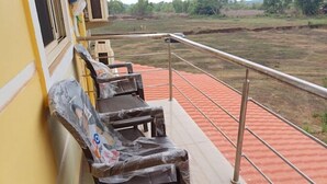 Un balcone con pavimento in tegole rosse, ringhiera in metallo e due sedie imbottite.