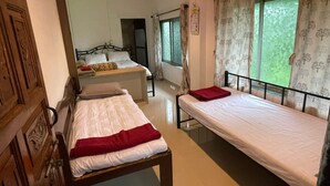 A room with two beds, a wooden door, a ceiling fan, and a window with curtains. - RS Farms (Bhiwandi)