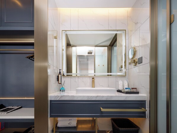 Un baño moderno con un espejo grande, un lavamanos blanco y un mueble de tocador oscuro.