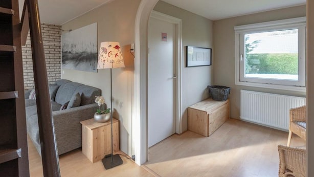En hyggelig stue med en sofa, en lampe, et indrammet billede, et vindue og en radiator.
