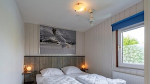 Et soveværelse med en seng, to sengeborde, en loftsvifte, et vindue med udsigt og et billede hængende på væggen.