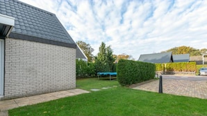 En boligejendom med en murstensvilla, en velplejet græsplæne og et tilstødende hus med et lignende tag.