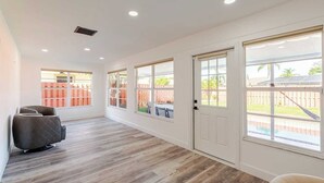 Un pasillo con piso de madera, paredes blancas y ventanas amplias.