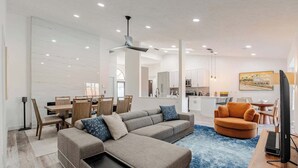 Una sala moderna con un sofá modular, un comedor y una cocina al fondo.