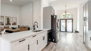 Una cocina moderna con una isla grande, electrodomésticos de acero inoxidable y un comedor con sillas de madera.