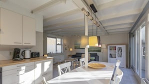 Een moderne keuken met witte kasten, een eettafel met stoelen en een hanglamp.