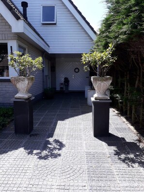 A paved pathway leading to a house with two large planters on either side. - Holiday Home Near Centre of Petten (Petten)