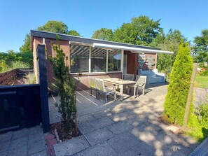 Ein modernes Haus mit Terrasse, Essbereich und kleinem Garten.
