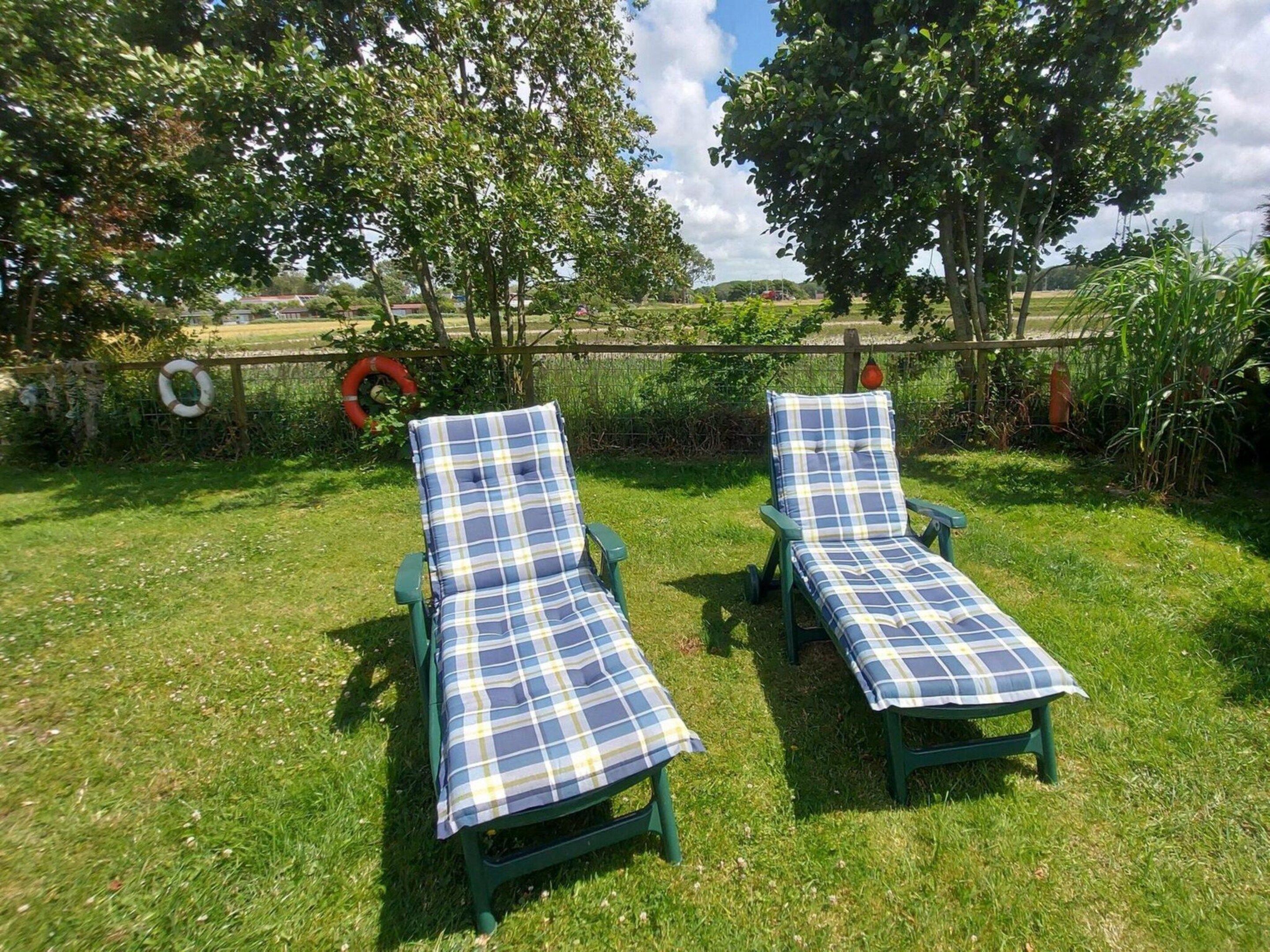Two green lounge chairs with blue and white checkered covers, positioned on a grassy lawn.