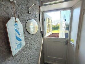 A door with a view of a garden, a welcome sign, and a wall-mounted light fixture. - Holiday Retreat in Sint Maartenszee (Sint Maartensvlotbrug)