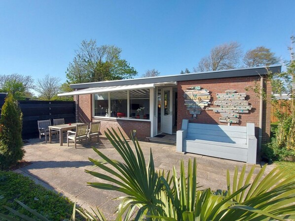 Une maison moderne dotée d’un patio, d’un espace salon extérieur et d’un mur d’escalade.