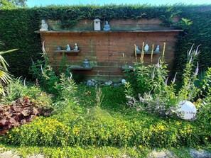 A garden with a wooden wall adorned with statues and a birdhouse. - Holiday Retreat in Sint Maartenszee (Sint Maartensvlotbrug)