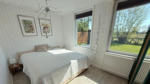 Ein Schlafzimmer mit einem Bett, einem Nachttisch, einem Fenster und einer Heizung.