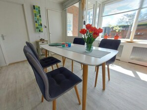 A dining area with a white table, four chairs, and a vase of red tulips. - Holiday Retreat in Sint Maartenszee (Sint Maartensvlotbrug)