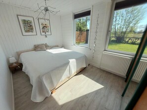 Une chambre à coucher avec un lit, une table de chevet, une fenêtre et un radiateur.