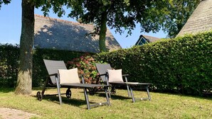 Two outdoor lounge chairs with wheels, positioned on a grassy area with a brick pathway. - 6-person Holiday Home With Garden (Sint Maartensvlotbrug)
