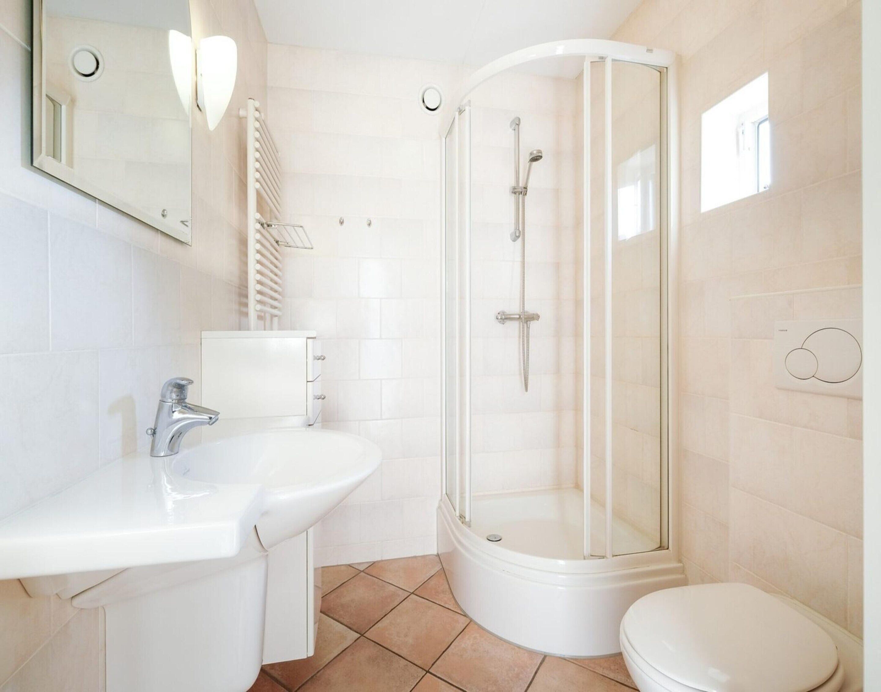 Ein modernes Badezimmer mit einer begehbaren Glasdusche, einem weißen Waschbecken und einer Toilette.