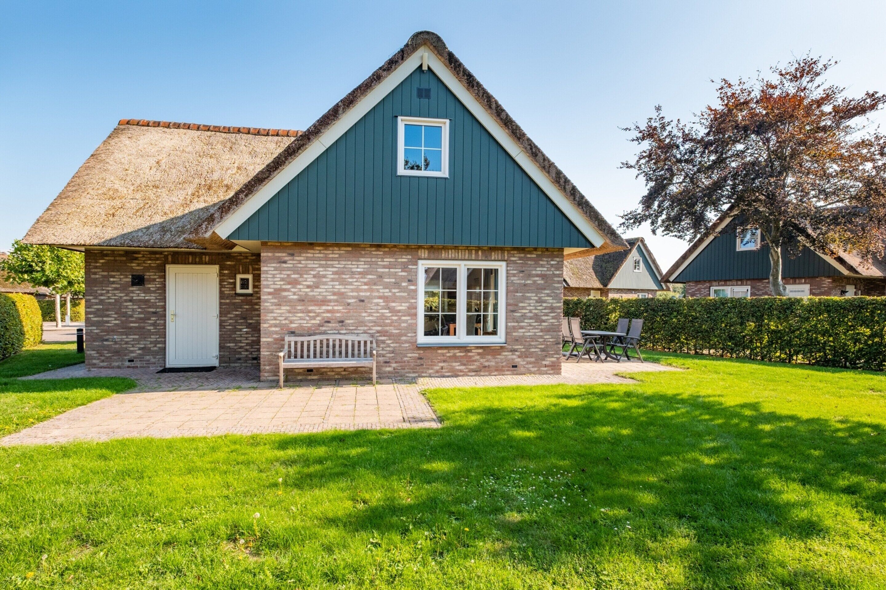 A house with a thatched roof, a brick exterior, and a well-maintained lawn.