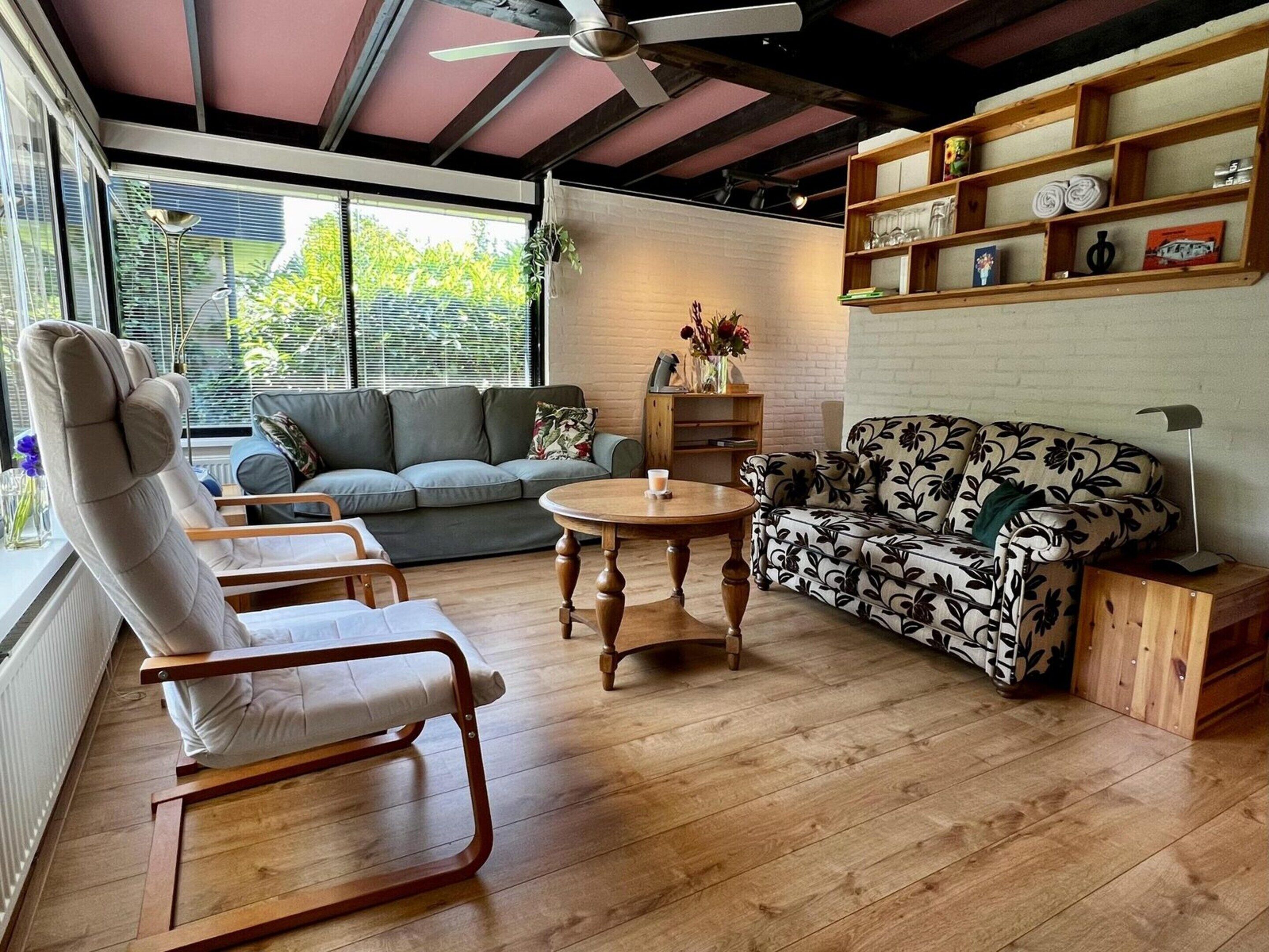 A living room with a sofa, two rocking chairs, a coffee table, and a bookshelf.