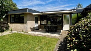 A modern house with a patio, a covered outdoor seating area, and a well-maintained lawn.